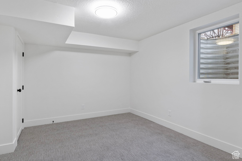 Additional living space with a textured ceiling and light carpet