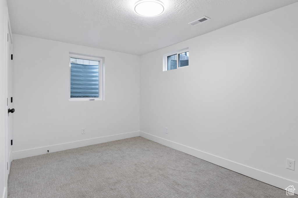 Carpeted empty room featuring a textured ceiling