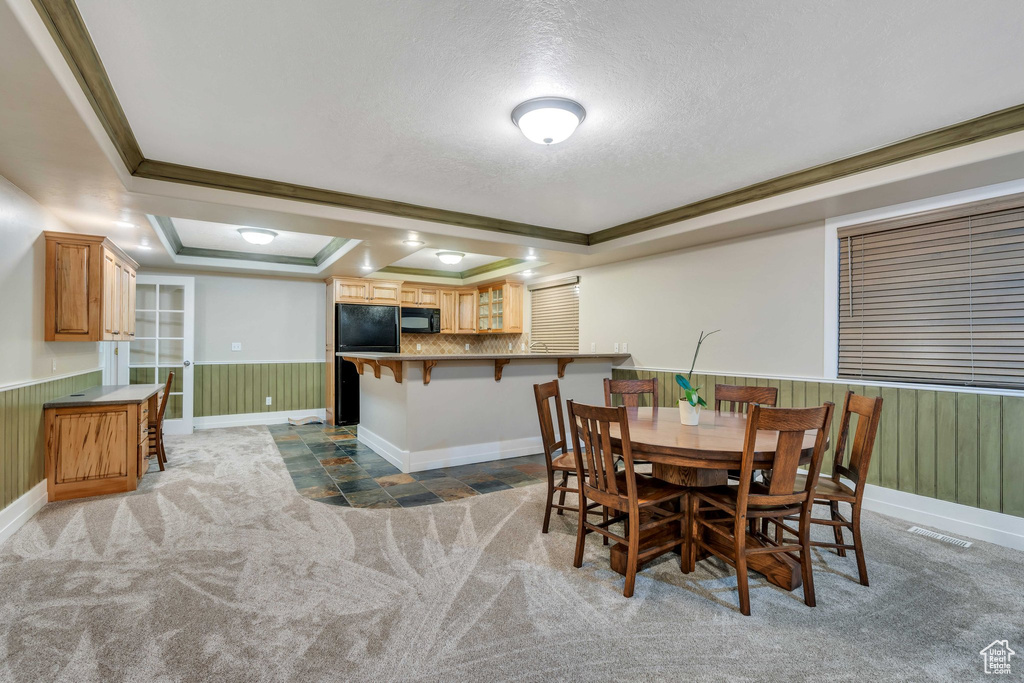 Dining space with a tray ceiling, crown molding, and a textured ceiling