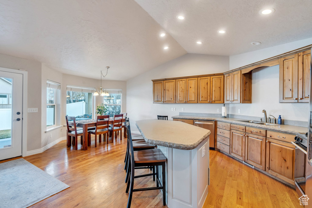 Kitchen featuring a kitchen breakfast bar, sink, decorative light fixtures, a notable chandelier, and a kitchen island