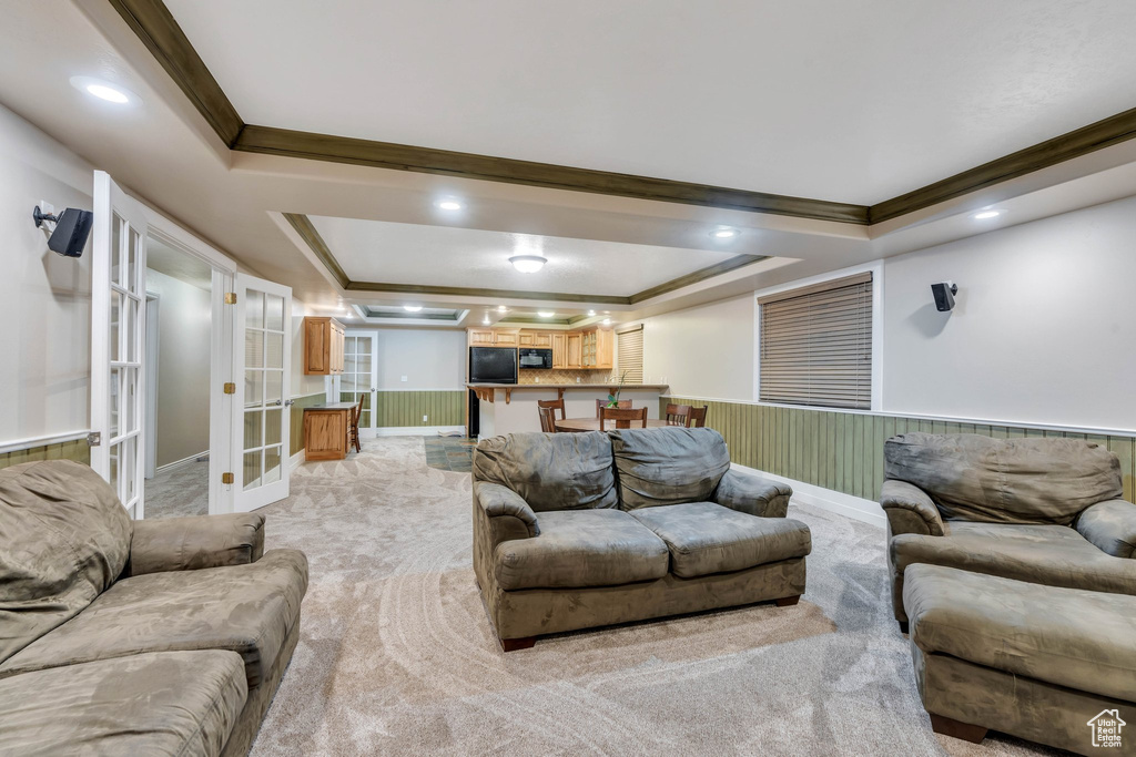 Carpeted living room featuring a tray ceiling, french doors, and ornamental molding