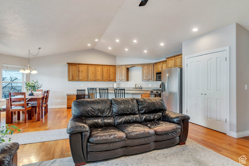 Living room with light hardwood / wood-style flooring, a chandelier, vaulted ceiling, and sink