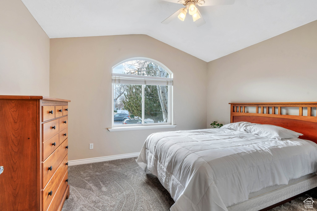 Carpeted bedroom with ceiling fan and lofted ceiling