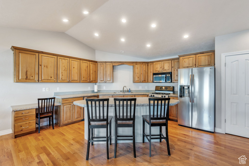 Kitchen featuring a center island, stainless steel appliances, light hardwood / wood-style flooring, and lofted ceiling