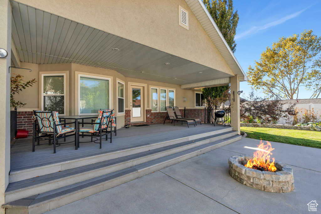 View of patio with a fire pit, a deck, and a grill