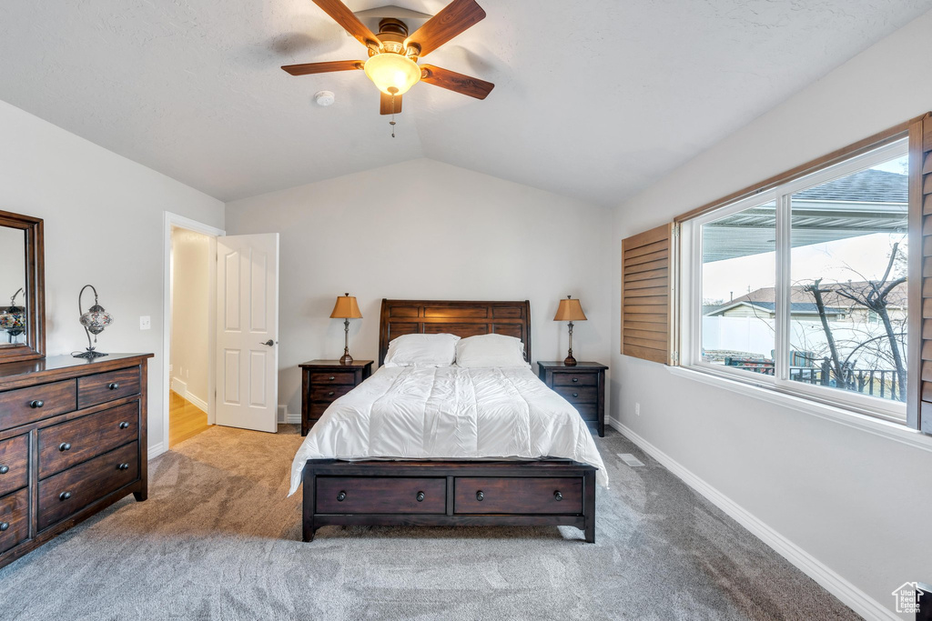 Carpeted bedroom featuring ceiling fan and lofted ceiling