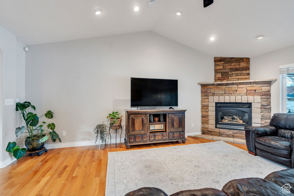 Living room with a fireplace, wood-type flooring, and lofted ceiling