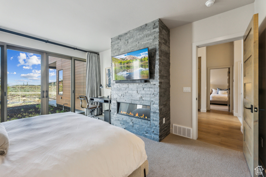 Carpeted bedroom featuring a stone fireplace