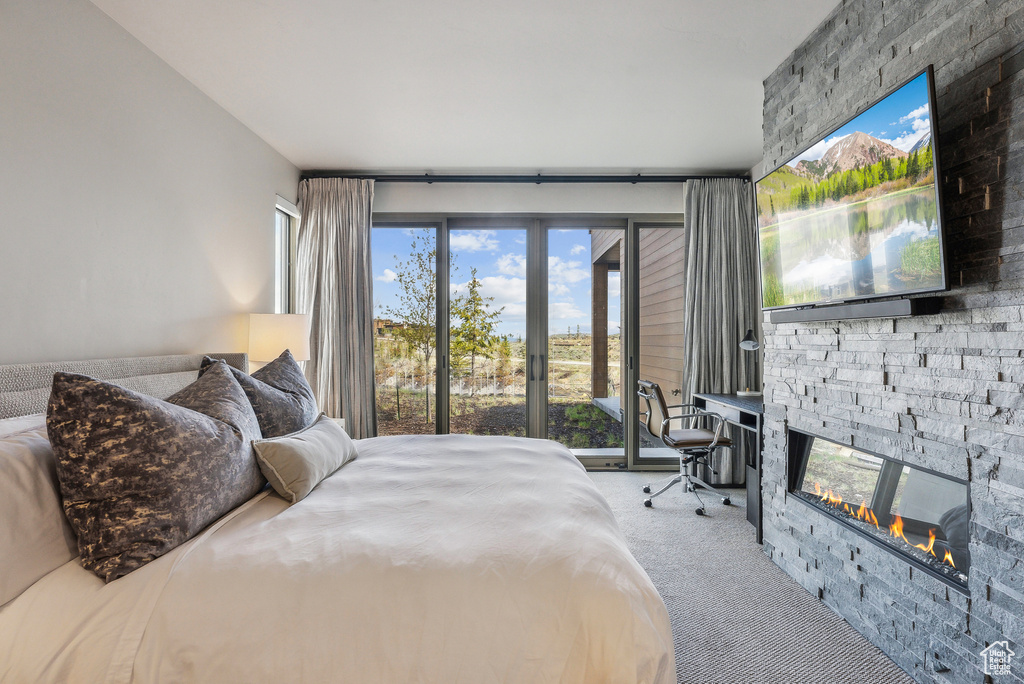 Carpeted bedroom with a fireplace and access to outside