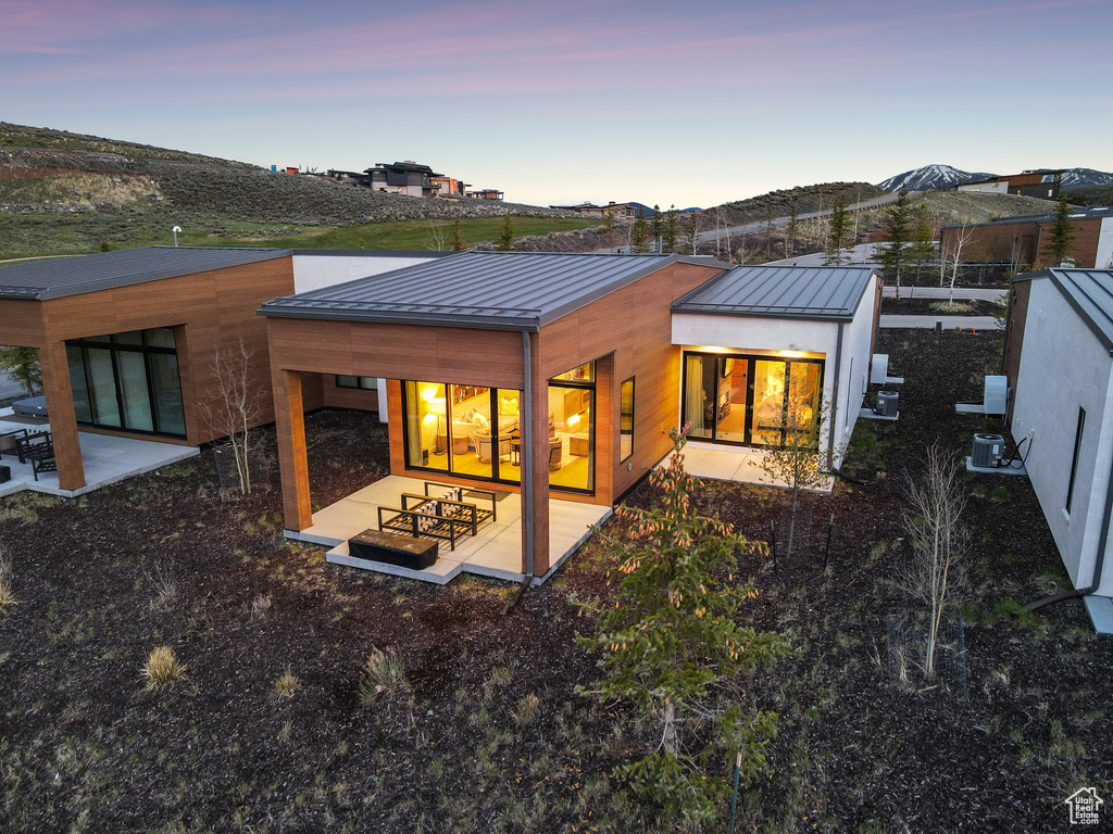Back of property at dusk featuring a standing seam roof, metal roof, and a patio area