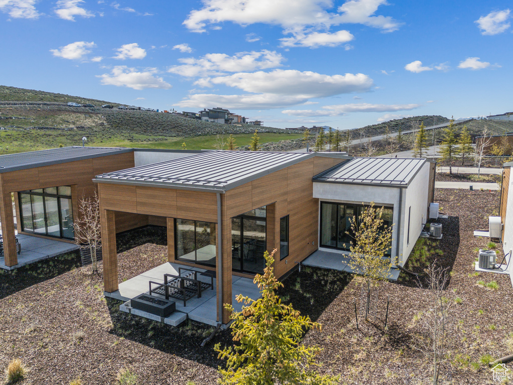 Rear view of house featuring a standing seam roof, a patio area, and metal roof