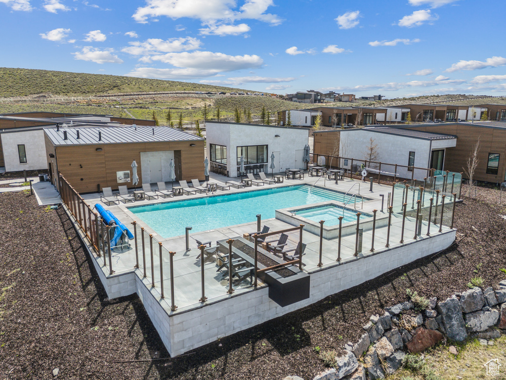 View of pool with fence, a pool with connected hot tub, and a patio