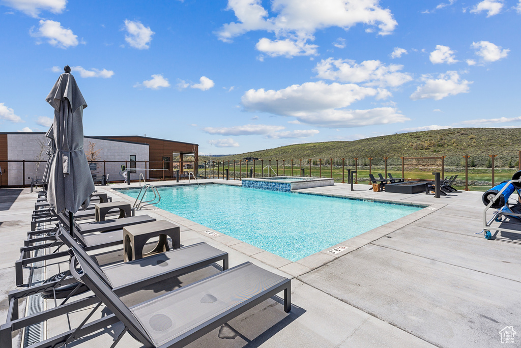 View of pool featuring a patio area, a pool with connected hot tub, and fence