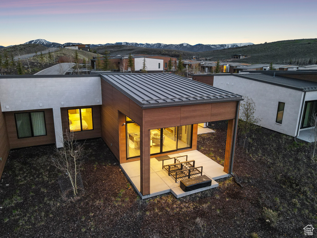 Back of house featuring a standing seam roof, a mountain view, metal roof, and a patio