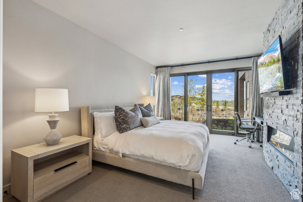 Carpeted bedroom with access to exterior and a fireplace