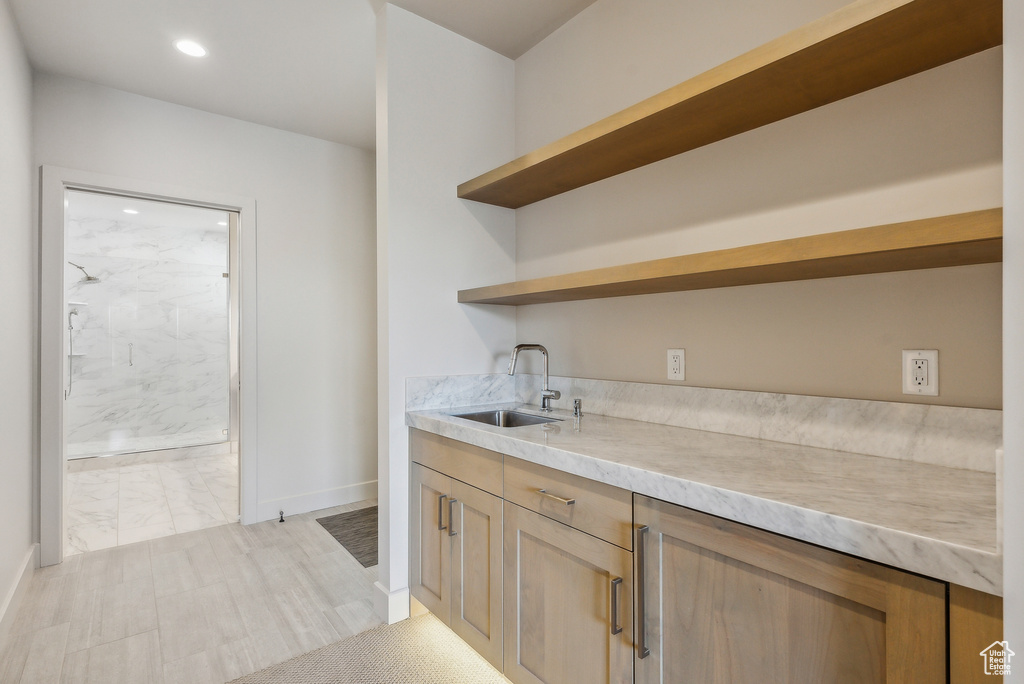 Bar area featuring a sink, recessed lighting, baseboards, and light marble finish floors