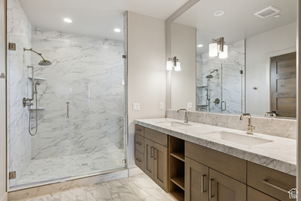 Full bath featuring marble finish flooring, a marble finish shower, recessed lighting, and double vanity