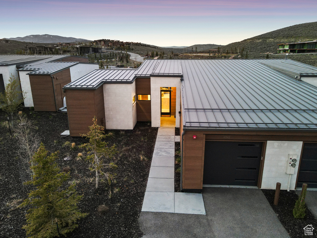 Modern home with a standing seam roof, metal roof, a mountain view, a garage, and driveway