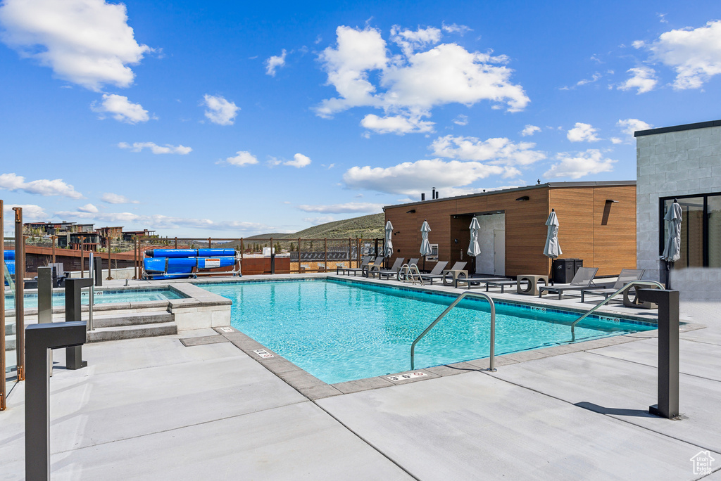 Community pool with a patio area, a jacuzzi, and fence