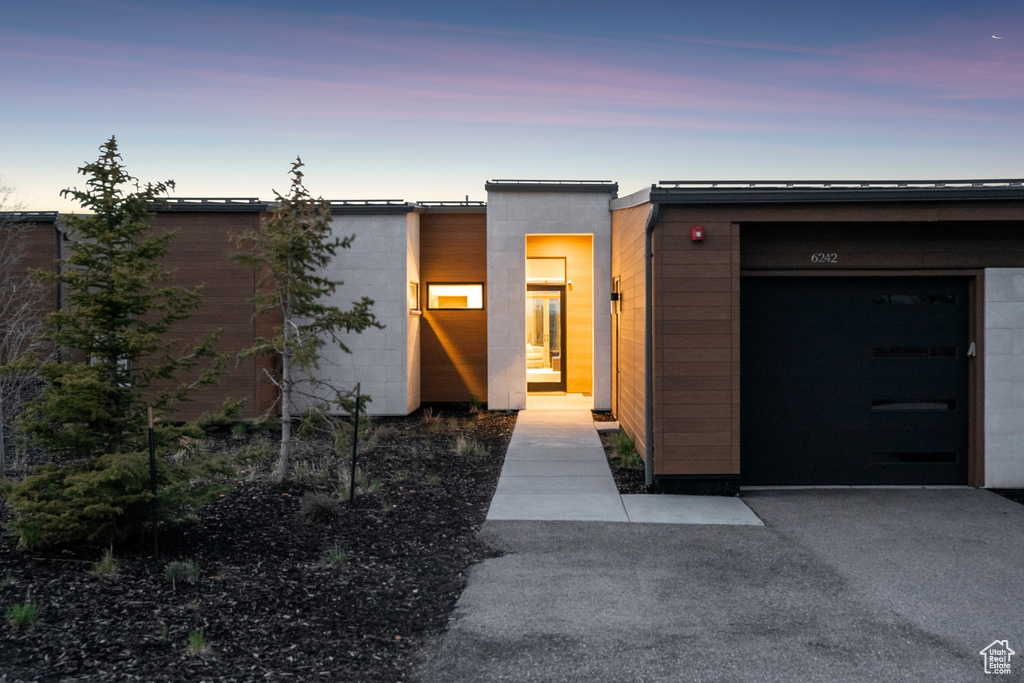 Exterior entry at dusk with concrete block siding and a garage