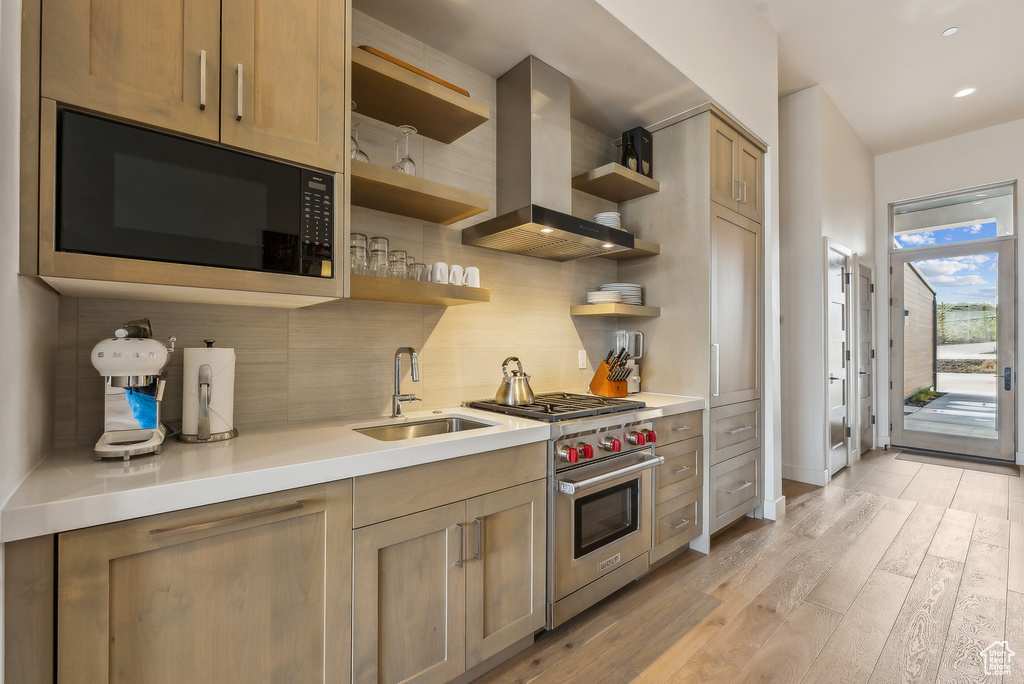 Kitchen with wall chimney exhaust hood, black microwave, luxury range, open shelves, and a sink