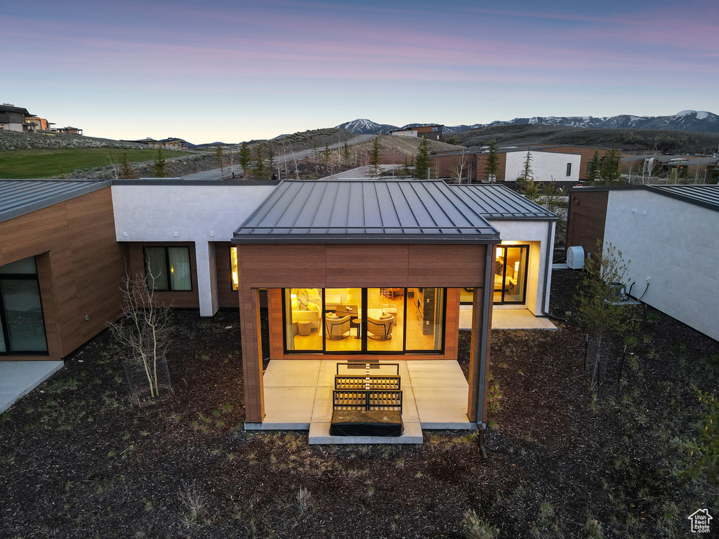 Back of house at dusk featuring a standing seam roof, a mountain view, and metal roof