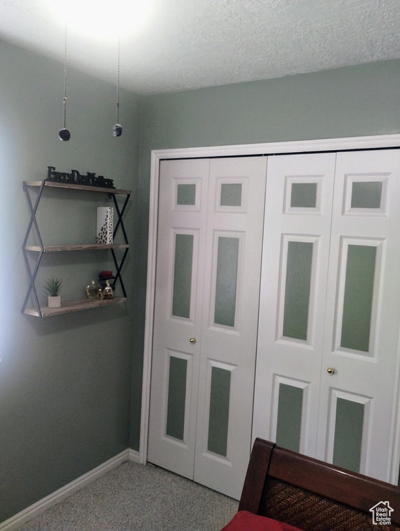 Unfurnished bedroom with baseboards, light carpet, a closet, and a textured ceiling