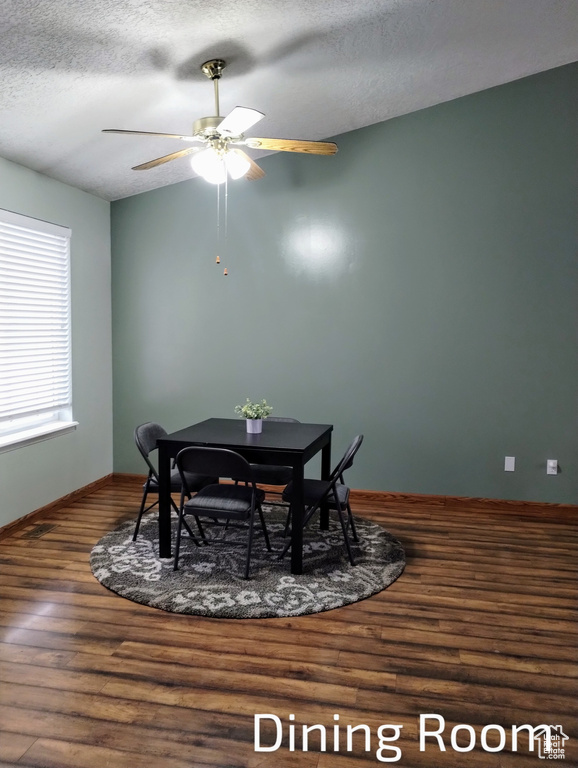 Dining room featuring a textured ceiling, baseboards, a ceiling fan, and wood finished floors