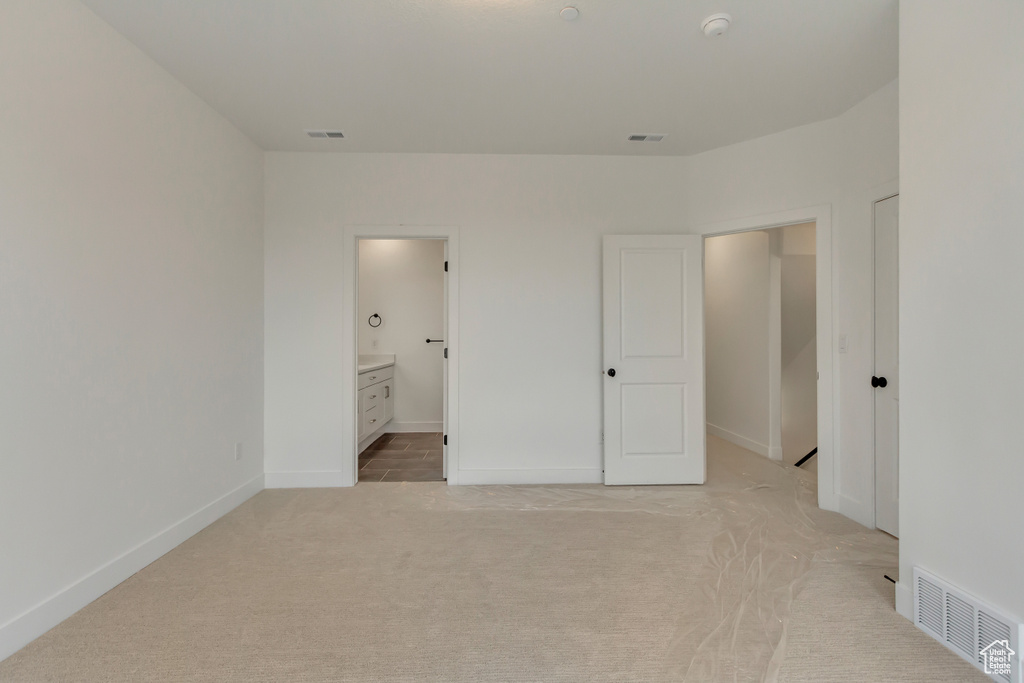Unfurnished bedroom featuring light colored carpet and ensuite bath