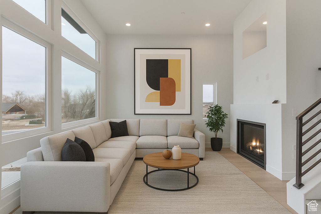 Living room with light wood-style floors, recessed lighting, and a glass covered fireplace