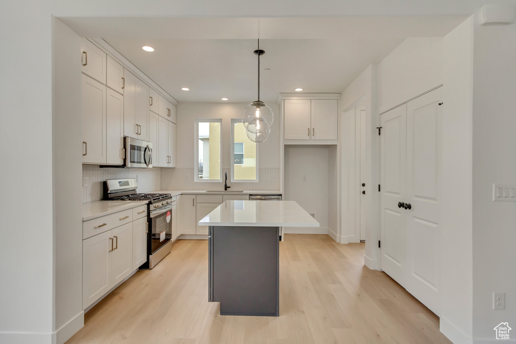 Kitchen featuring stainless steel appliances, light wood-style flooring, tasteful backsplash, white cabinets, and recessed lighting