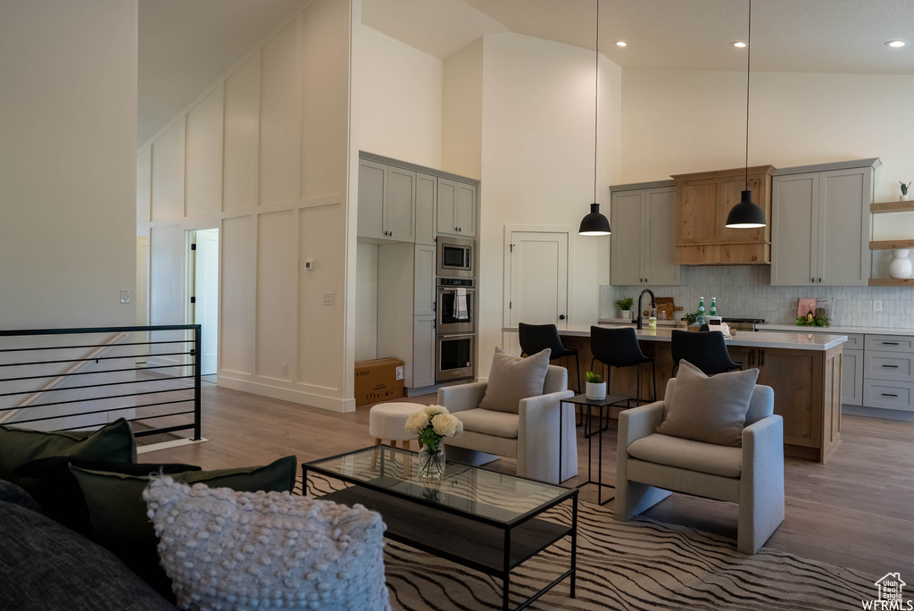 Living room featuring sink, high vaulted ceiling, and light wood-type flooring