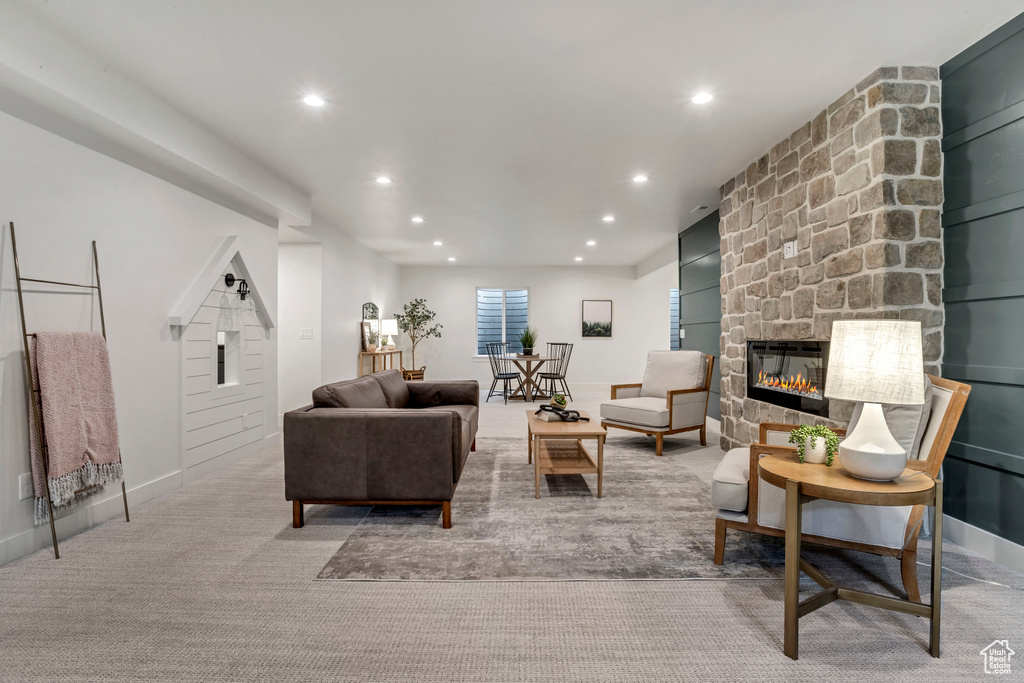 Living room with baseboards, a stone fireplace, light colored carpet, and recessed lighting