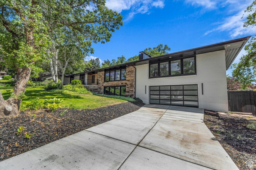 View of front of home featuring driveway, a garage, and a front lawn