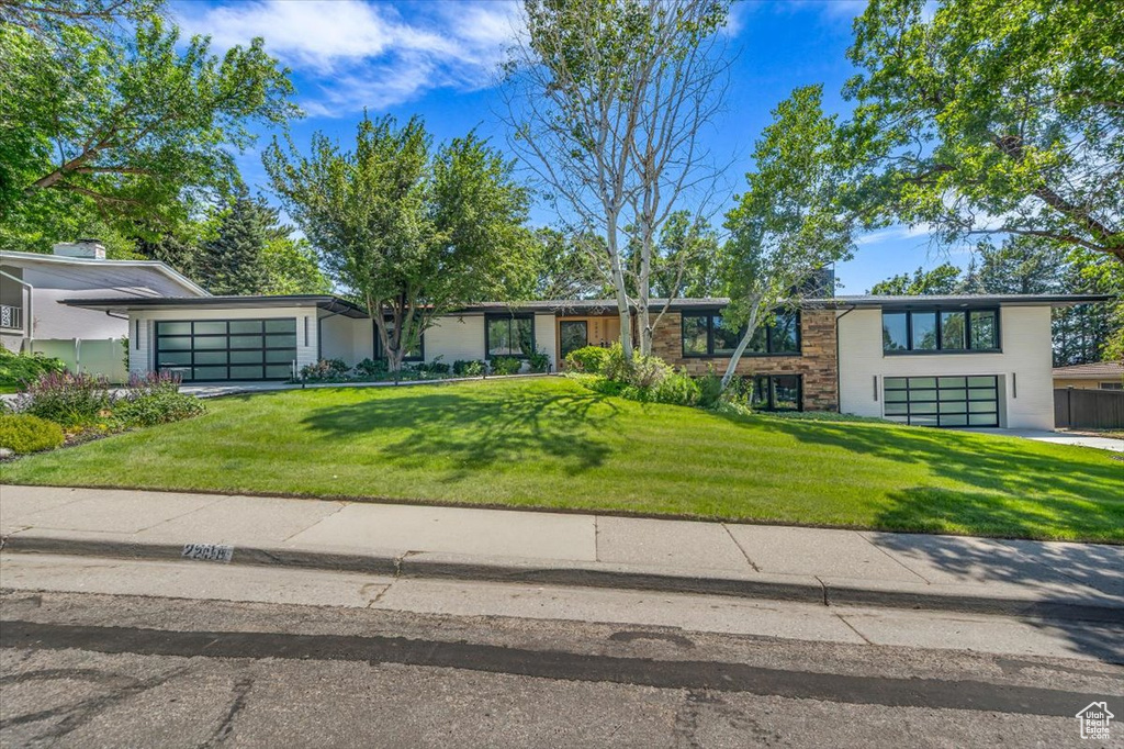 View of front of house with a front lawn, driveway, and an attached garage