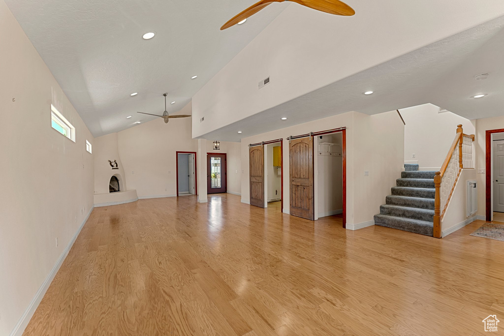 Unfurnished living room featuring a ceiling fan, light wood-style flooring, recessed lighting, baseboards, and high vaulted ceiling