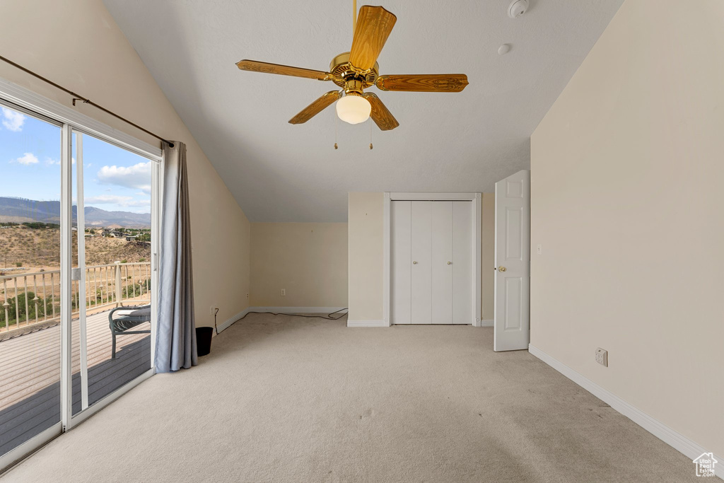 Bonus room featuring lofted ceiling, a mountain view, light colored carpet, baseboards, and a ceiling fan
