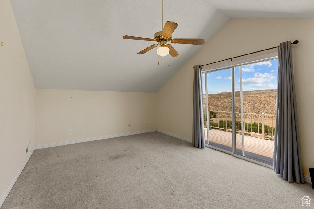 Additional living space featuring vaulted ceiling, light colored carpet, baseboards, and a ceiling fan