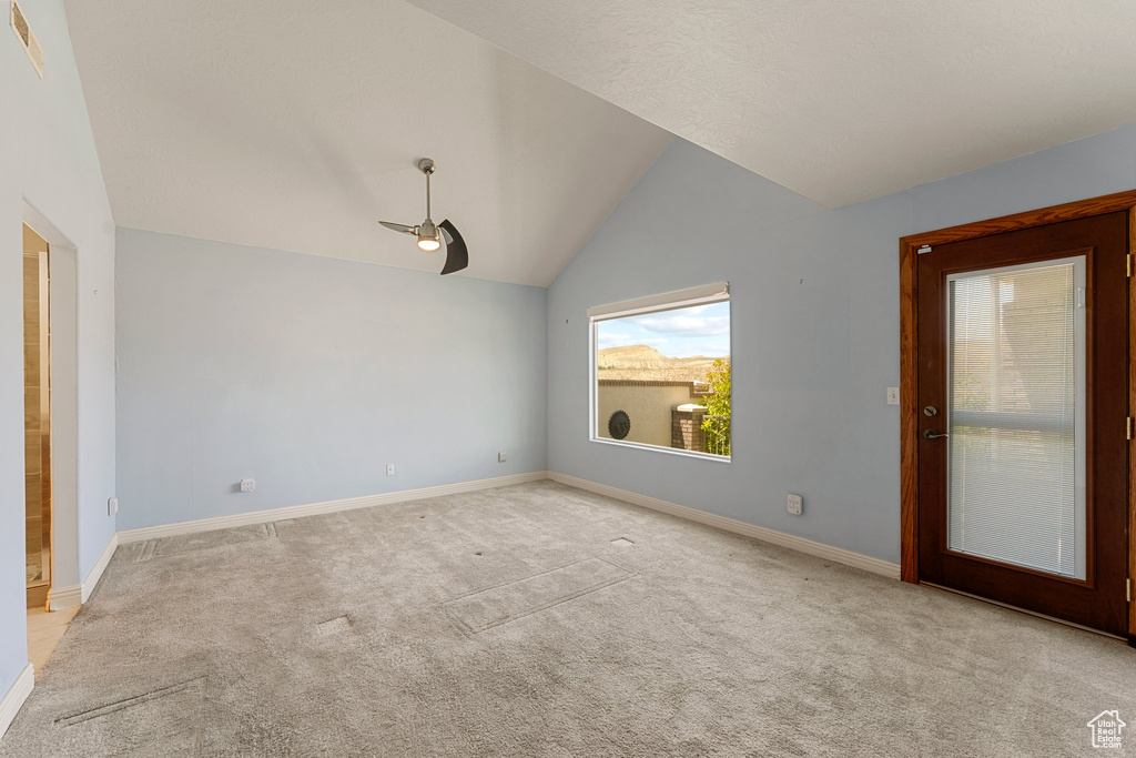 Carpeted empty room featuring a ceiling fan, vaulted ceiling, and baseboards