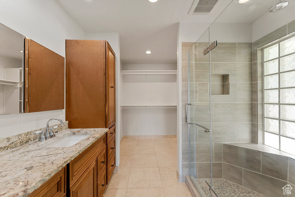 Bathroom featuring vanity, a stall shower, a walk in closet, tile patterned floors, and recessed lighting
