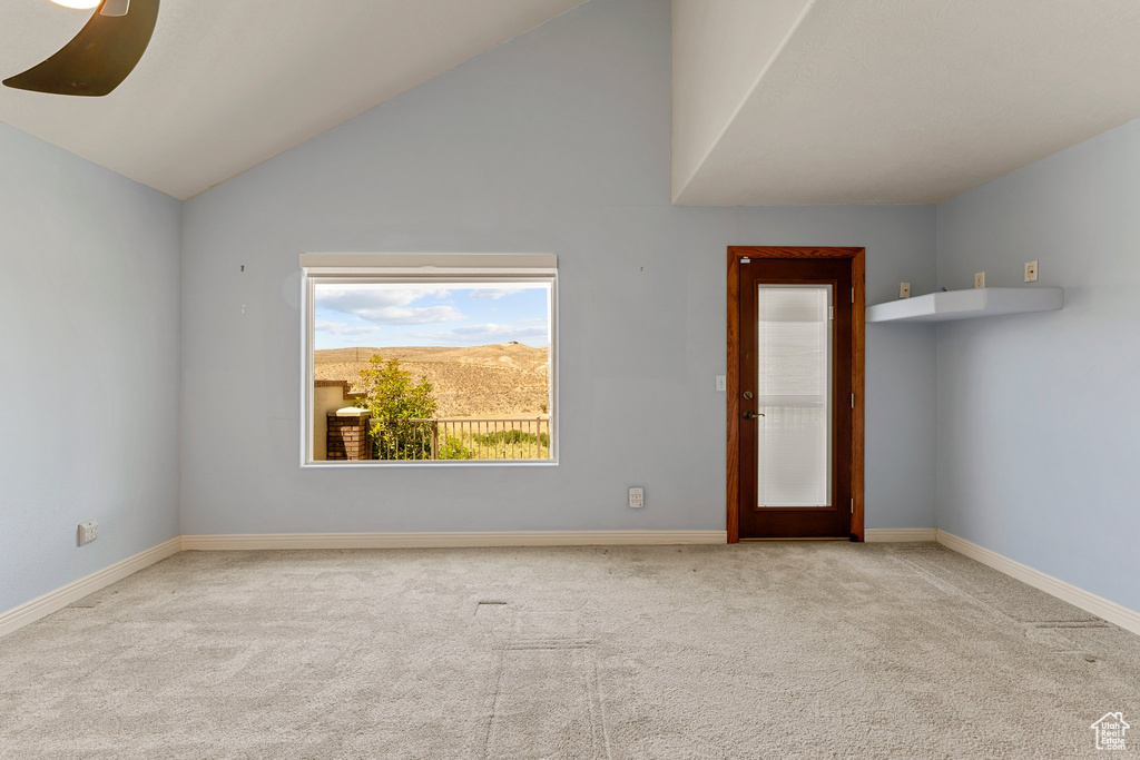 Empty room featuring carpet, baseboards, and lofted ceiling