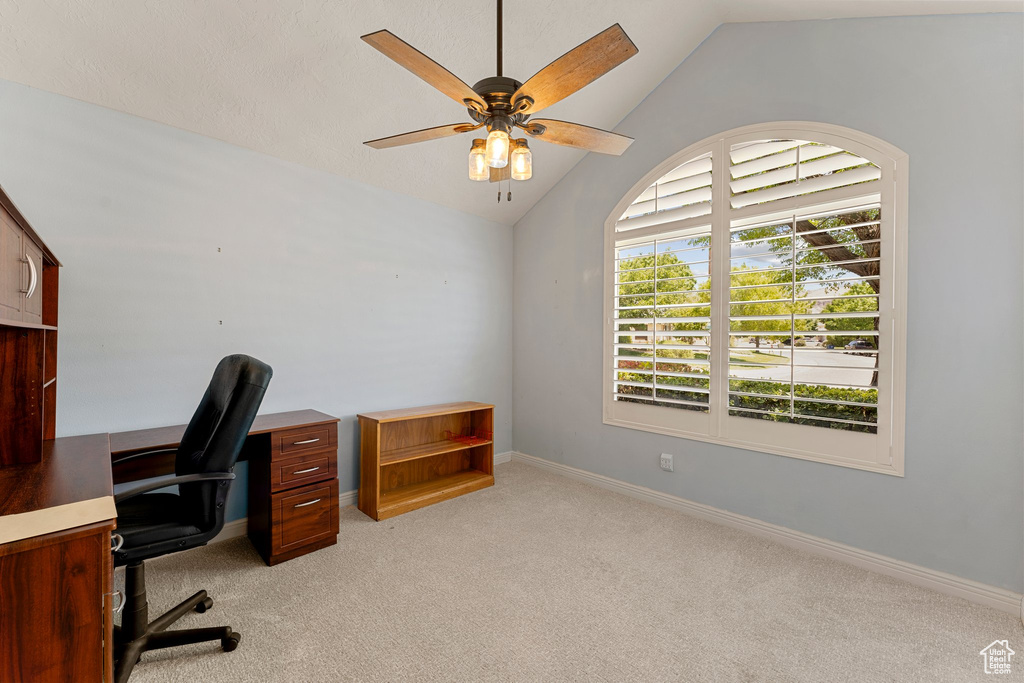 Unfurnished office with lofted ceiling, ceiling fan, light carpet, and baseboards