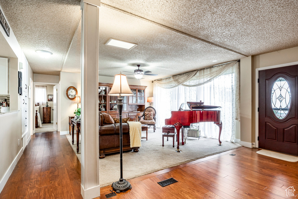 Entryway with ceiling fan, a textured ceiling, hardwood / wood-style floors, baseboards, and visible vents