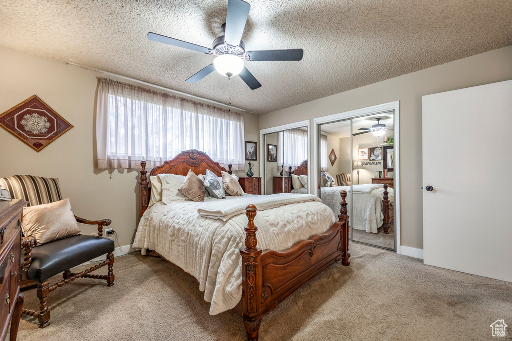 Bedroom featuring two closets, baseboards, ceiling fan, a textured ceiling, and carpet