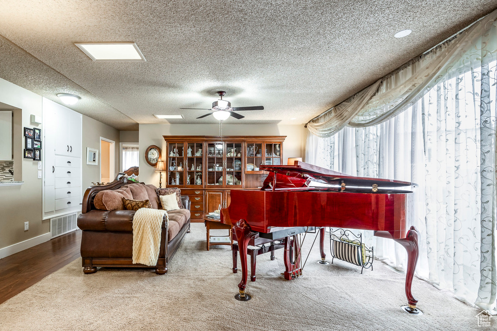Living area featuring visible vents, a ceiling fan, a textured ceiling, and a wealth of natural light