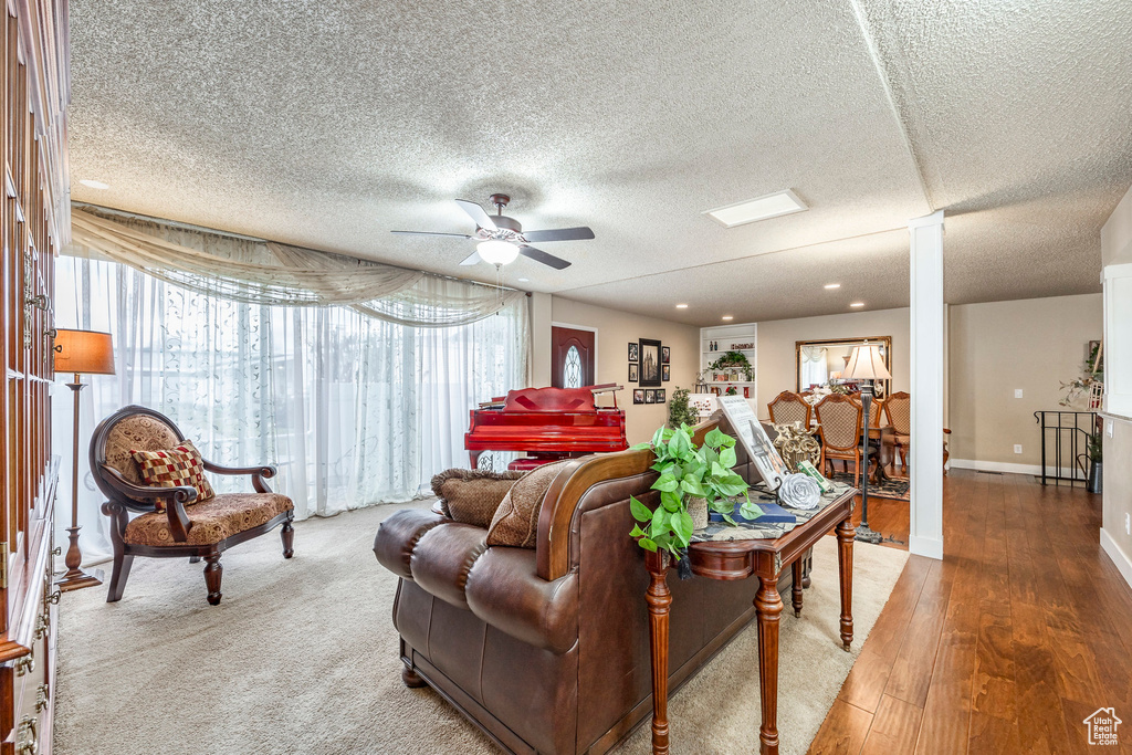 Living area with ceiling fan, decorative columns, a textured ceiling, wood finished floors, and recessed lighting
