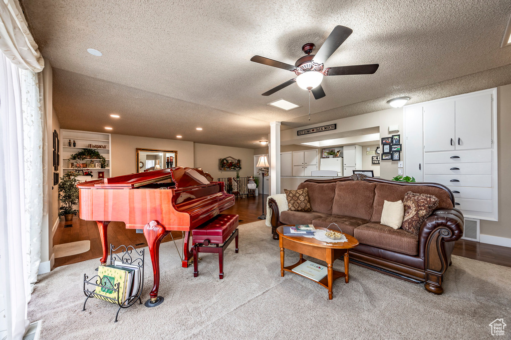 Carpeted living room with a ceiling fan, a textured ceiling, recessed lighting, and visible vents