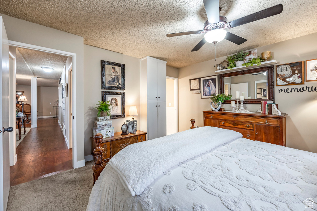 Carpeted bedroom with a ceiling fan and a textured ceiling