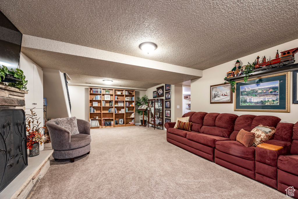 Living area featuring a fireplace, carpet, and a textured ceiling