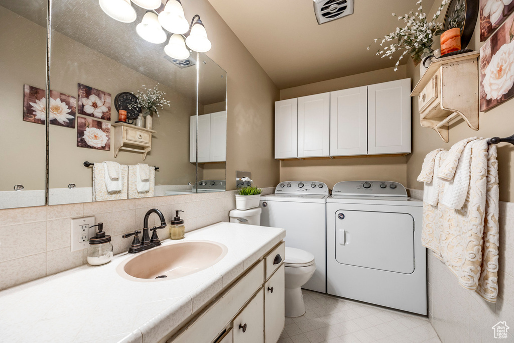 Bathroom featuring vanity, visible vents, toilet, and washer and dryer